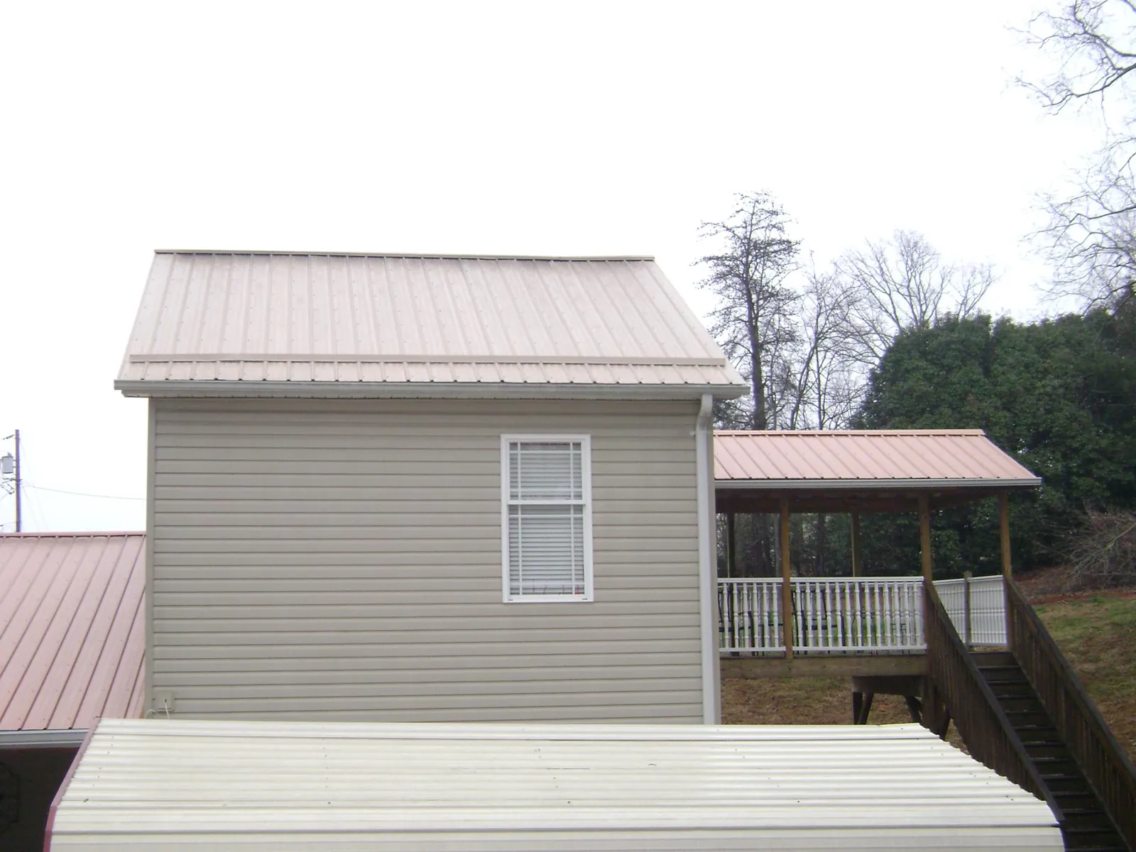 Tan metal roofs on a two story addition and attached porch, from a Roof Replacement job in Allenhurst
